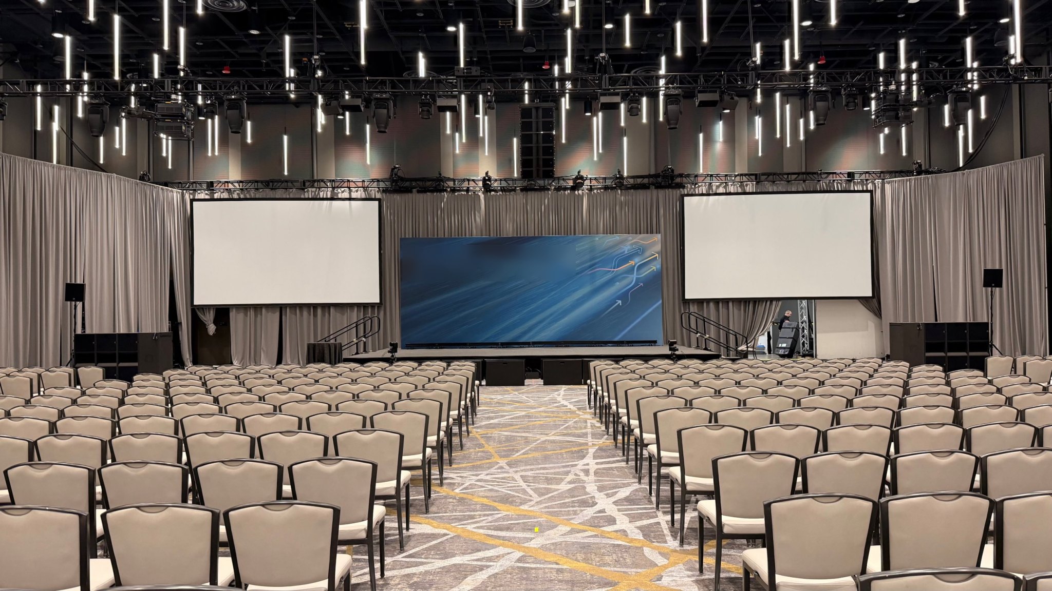 Stage set with twin projection screens, line arrays and lighting rig before doors open